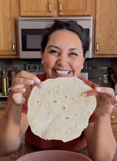 a woman holding up a tortilla in front of her face and smiling at the camera