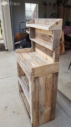 a wooden bench made out of pallets sitting on the side of a garage floor