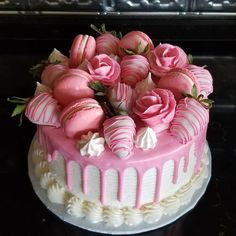 there is a cake with pink frosting and strawberries on the top, decorated with roses