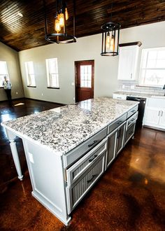 a large kitchen island in the middle of a room with wood floors and white cabinets