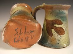 two ceramic mugs with writing on them, one is brown and the other is green