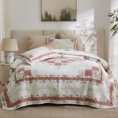 a bedroom with a bed covered in a quilt and pillows