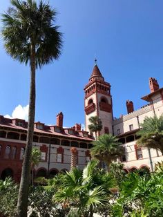 an old building with palm trees in the foreground and a blue sky behind it