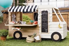 an ice cream cart with a chalkboard sign on the side and balloons in the background