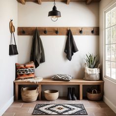 a wooden bench sitting under a window next to a coat rack and potted plant