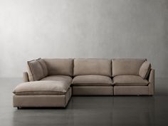 a large sectional couch sitting on top of a floor next to a chair and ottoman