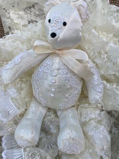 a white teddy bear sitting on top of lace