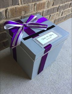 a gray box with a purple ribbon on the top and a white card in the middle