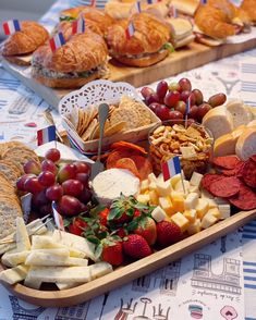 an assortment of cheeses, crackers and fruit on a tray