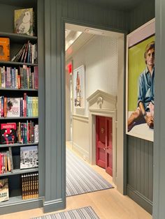 an open door leading to a library with bookshelves and pictures on the walls