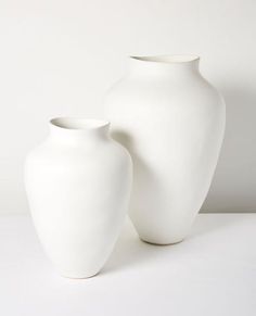 two white vases sitting next to each other on a table