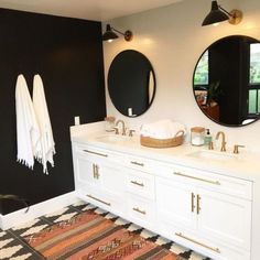 a black and white bathroom with two round mirrors