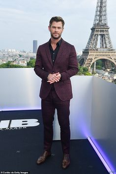 a man standing in front of the eiffel tower wearing a suit and tie