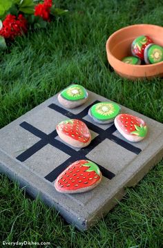 some strawberries and kiwis are sitting on a board game in the grass