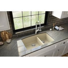 a kitchen sink sitting on top of a counter next to a window with a potted plant