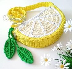 a crocheted lemon slice with two green leaves on it and some daisies