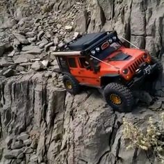 an orange jeep is parked on the side of a rocky cliff with its doors open