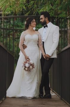 a bride and groom standing on a bridge