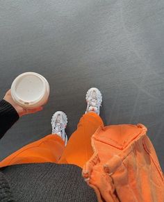 a person sitting on the ground holding a white cup