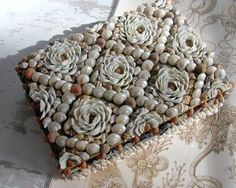 there is a decorative box made out of shells and flowers on the tablecloths