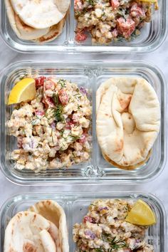 four plastic containers filled with food and some lemon wedges next to eachother