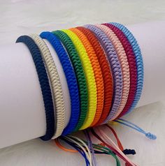 a stack of multicolored bracelets sitting on top of a white roll