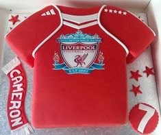 a cake in the shape of a liverpool shirt with stars and ribbons around it, on top of a white box