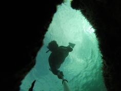 a person is swimming in the water near some rocks and corals with their feet up