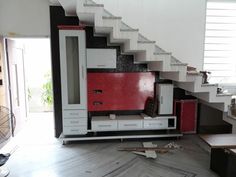 a living room with white and red furniture on the floor next to a stair case