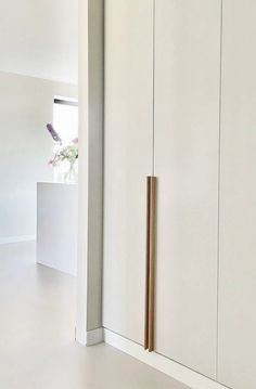 an empty room with white cupboards and gold handles