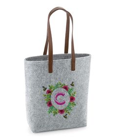 a handbag with the letter c on it and flowers in pink, green, red and purple