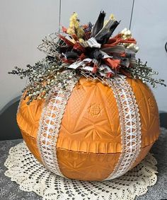 an orange pumpkin decorated with crochet and flowers