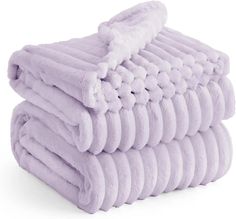 a stack of lavender colored towels folded on top of each other in front of a white background