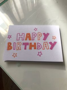 a card with the words happy birthday written in orange and pink on top of it