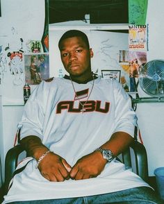 a man sitting in a chair with his arms crossed, wearing a white shirt that says usa