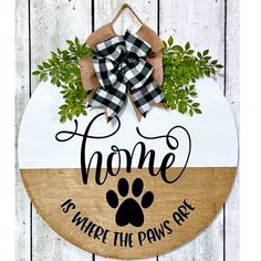 a wooden sign that says home is where the paws are