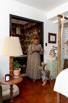 a woman standing next to a dog in a bedroom