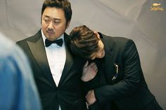 a man in a tuxedo is comforted by another man wearing a bow tie