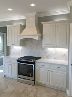 a stove top oven sitting inside of a kitchen next to white cupboards and drawers