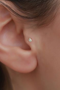 a woman's ear is shown with a small diamond in the middle