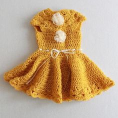 a crocheted yellow dress with white flowers on it