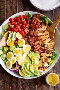 a salad with hard boiled eggs, bacon, tomatoes and avocado in it