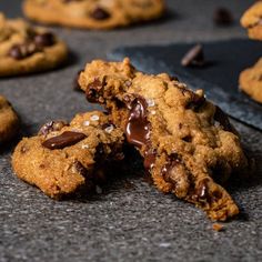 chocolate chip cookies on a table with one broken in half and the other partially eaten