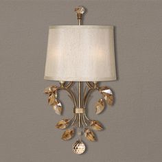 a wall light with a white shade on it's face and gold leaf accents