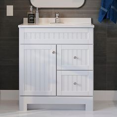 a white bathroom vanity with a mirror above it