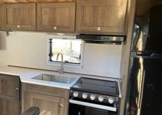 a kitchen area with an oven, sink and refrigerator in a trailer or camper