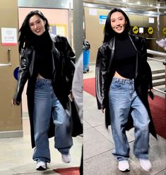 two women in black jackets and jeans are walking through an airport terminal, one is smiling at the camera