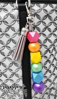 a rainbow bag charm hanging from a black and white purse