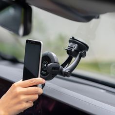 a person holding a cell phone in their hand while sitting in a car with the dash camera attached to it