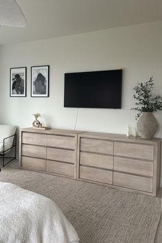 a bed room with a neatly made bed and a flat screen tv on the wall